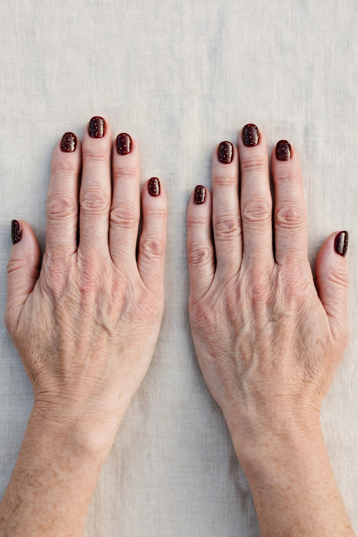 Dark Cherry Velvet Short Nails with a glassy gel finish and tiny gold dots