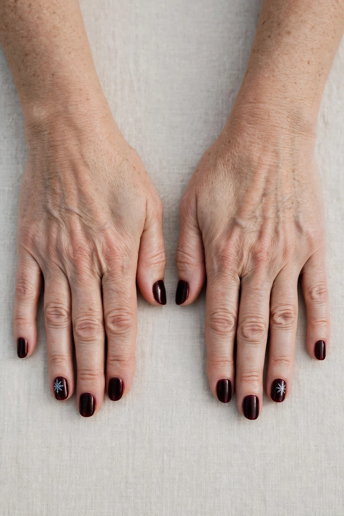Dark Cherry Velvet Short Nails with a satin finish and a delicate snowflake on the ring finger