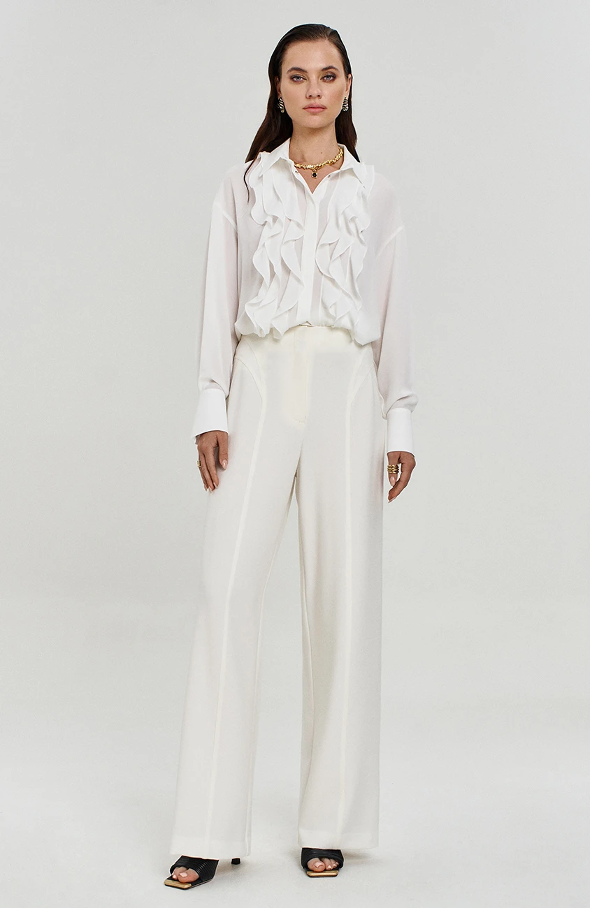 White Ruffle Blouse and Trousers with a gold pendant necklace