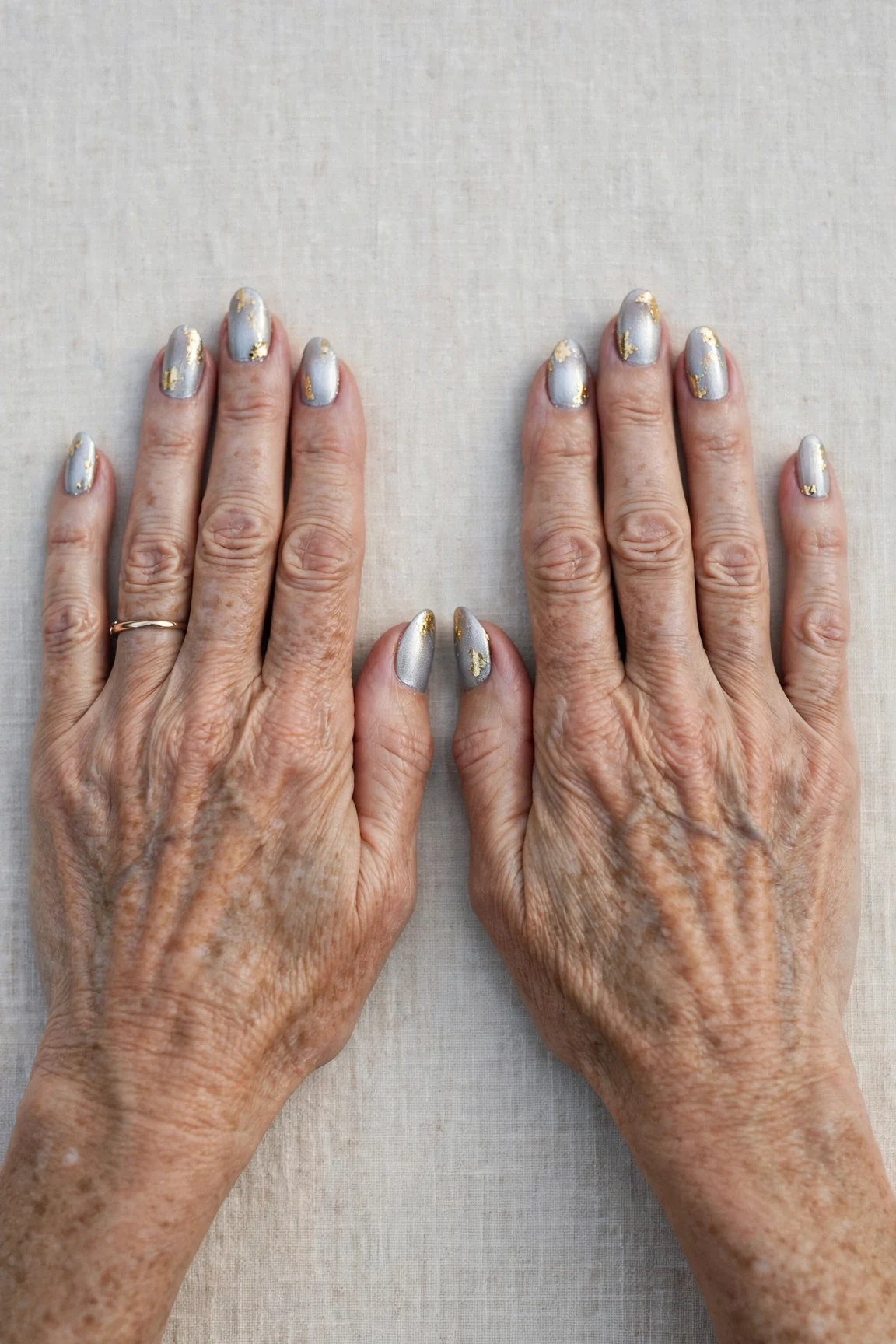 Icy Silver Frosted Almond Nails with a high-gloss finish and gold foil accents