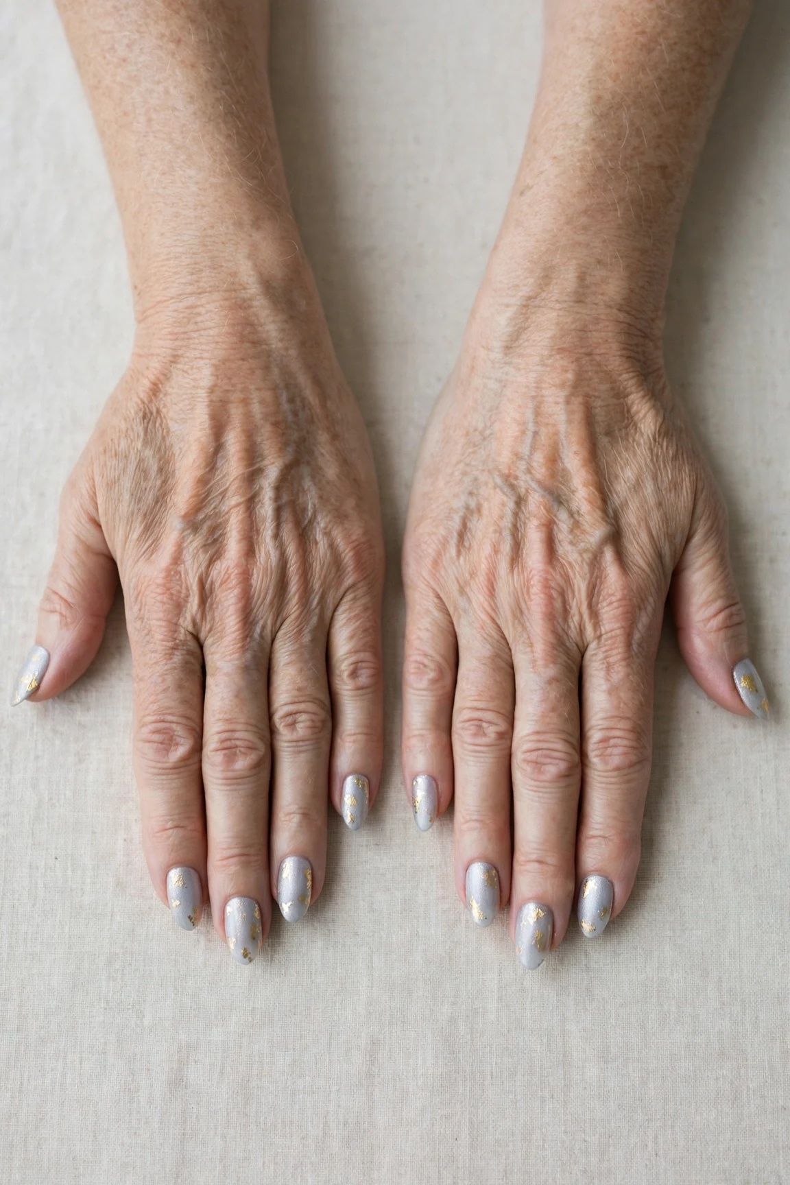 Icy Silver Frosted Almond Nails with a soft matte finish and gold foil accents