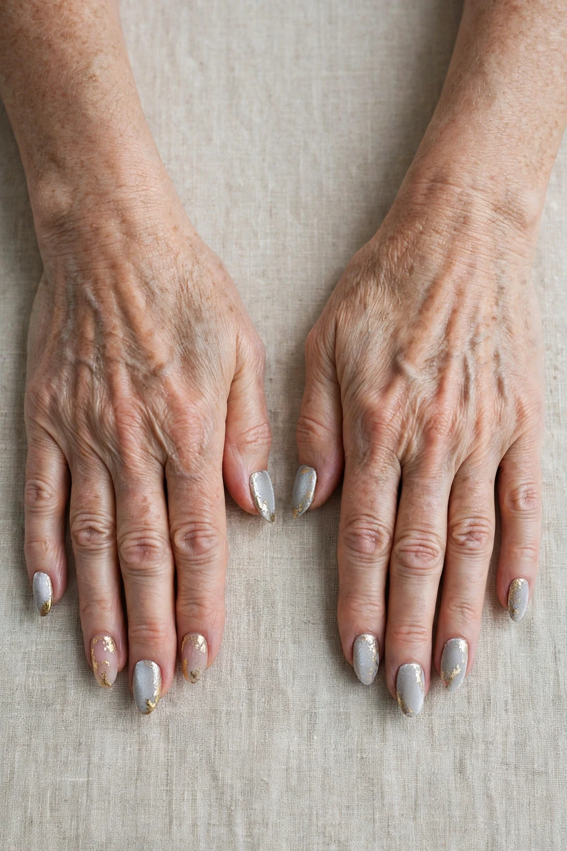 Icy Silver Frosted Almond Nails with a velvet matte finish and gold foil accents