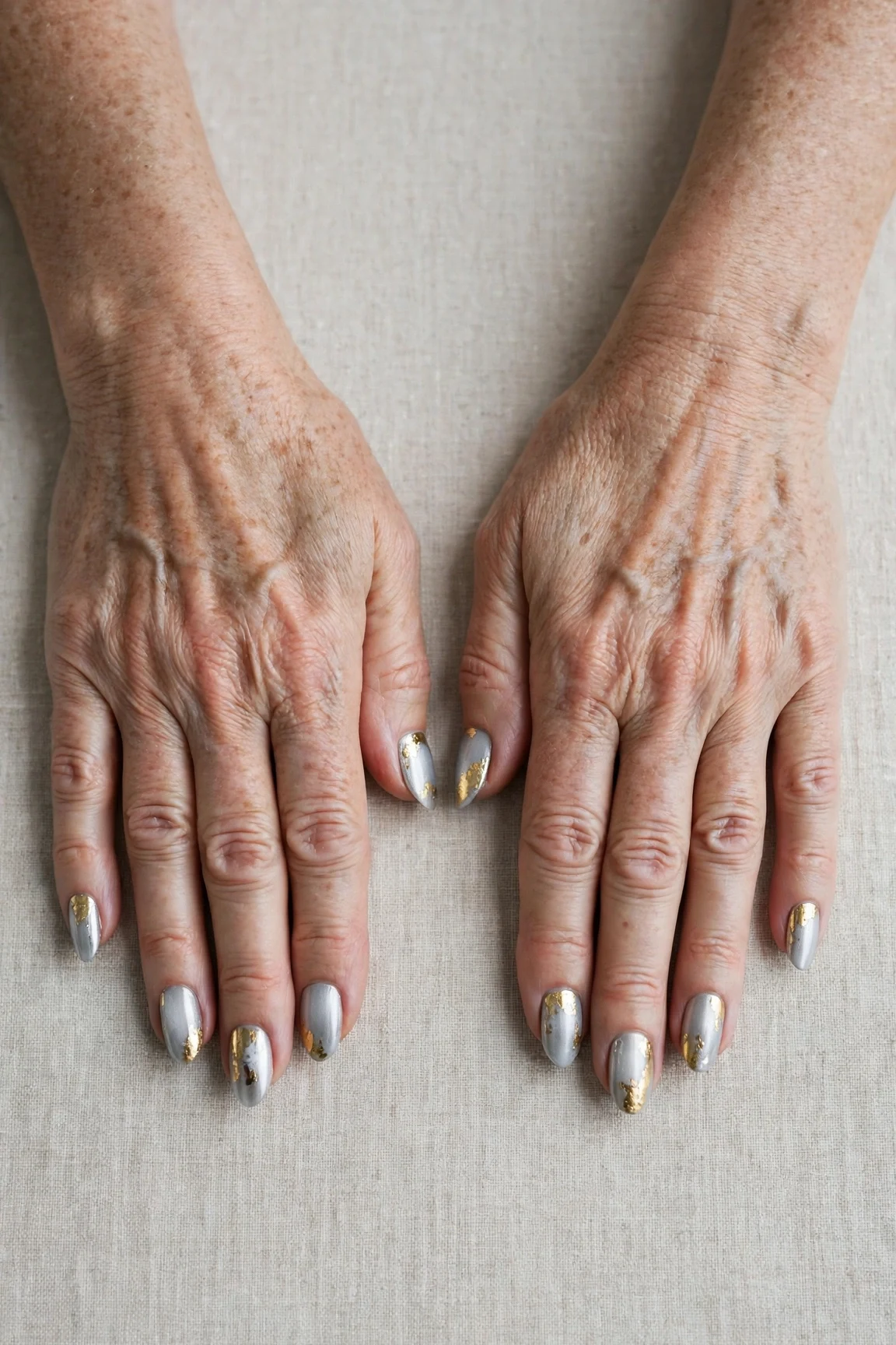 Icy Silver Frosted Almond Nails with a chrome shine and gold foil accents