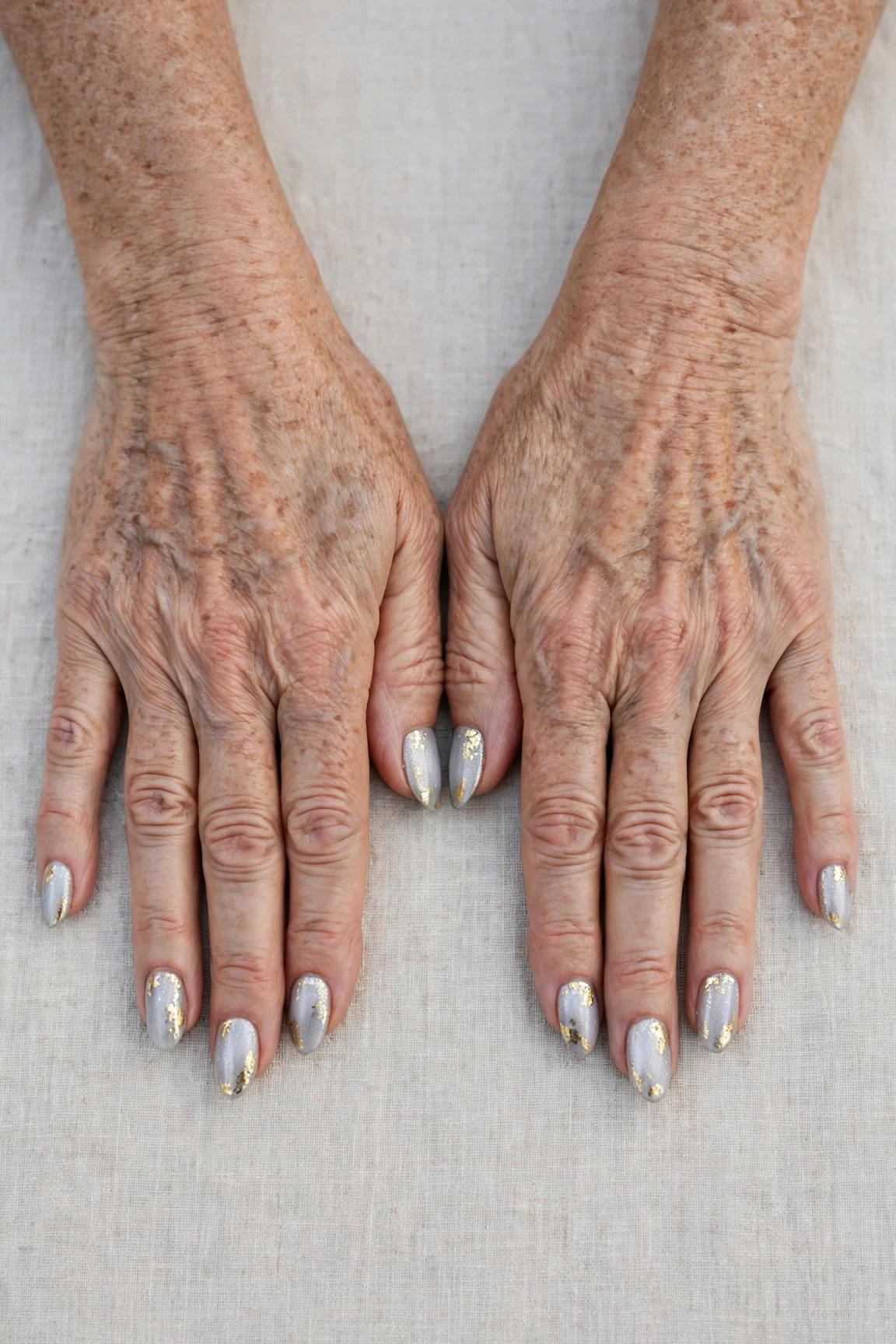 Icy Silver Frosted Almond Nails with a frosted shimmer finish and gold foil accents