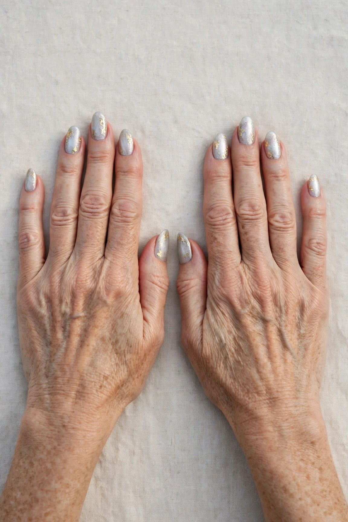 Icy Silver Frosted Almond Nails with a pearl shimmer finish and gold foil accents