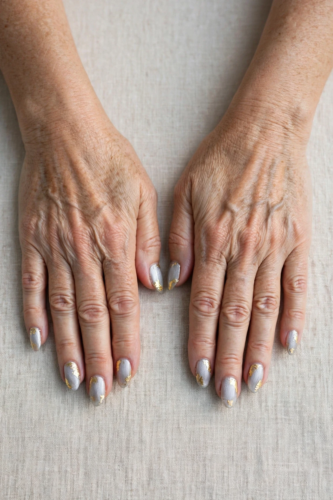 Icy Silver Frosted Almond Nails with a glassy gel finish and gold foil accents