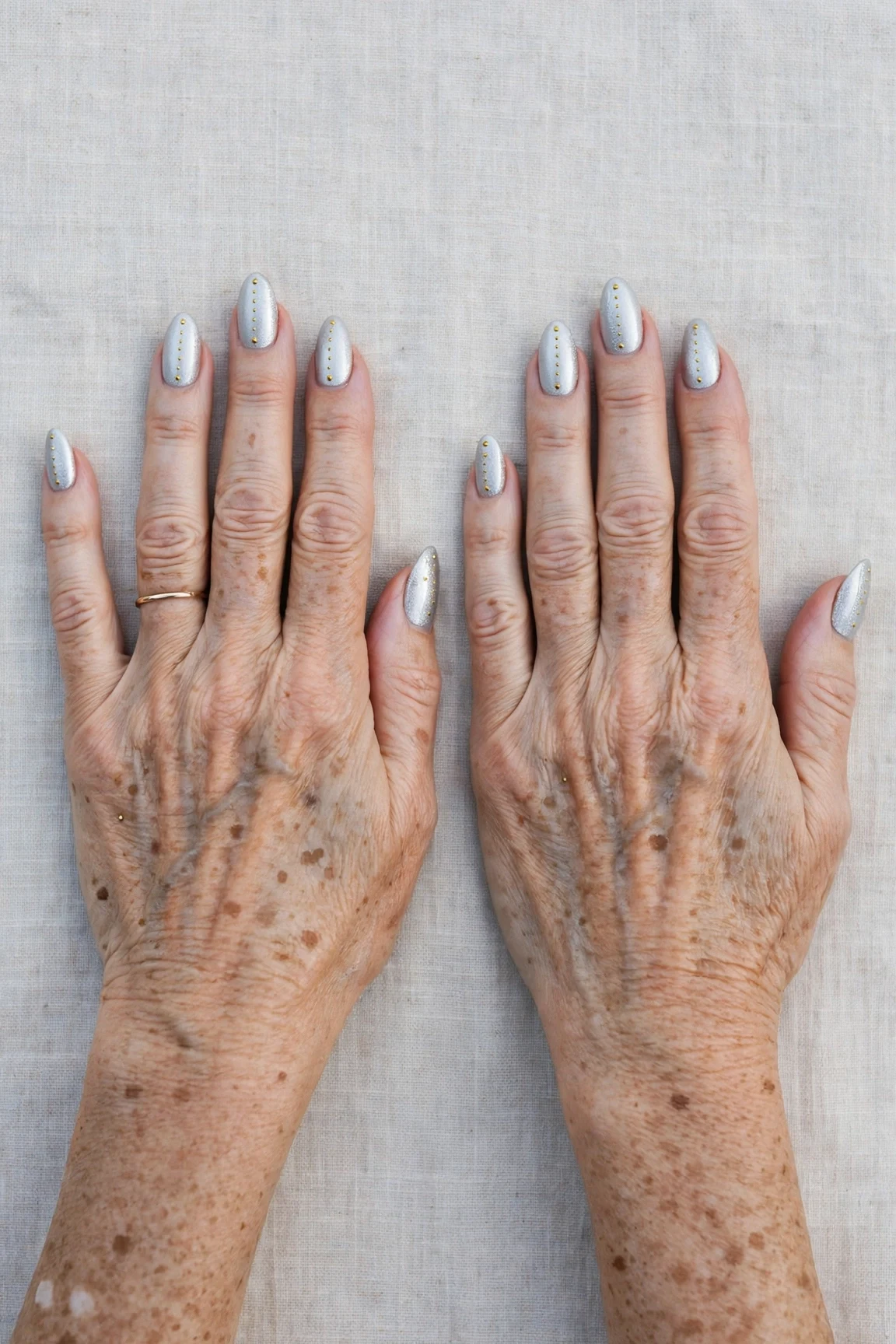 Icy Silver Frosted Almond Nails with a high-gloss finish and tiny gold dots