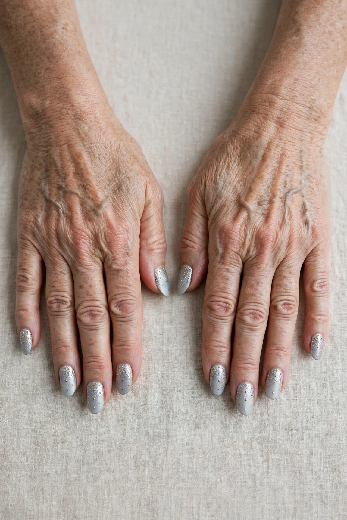 Icy Silver Frosted Almond Nails with a glitter gradient finish and tiny gold dots
