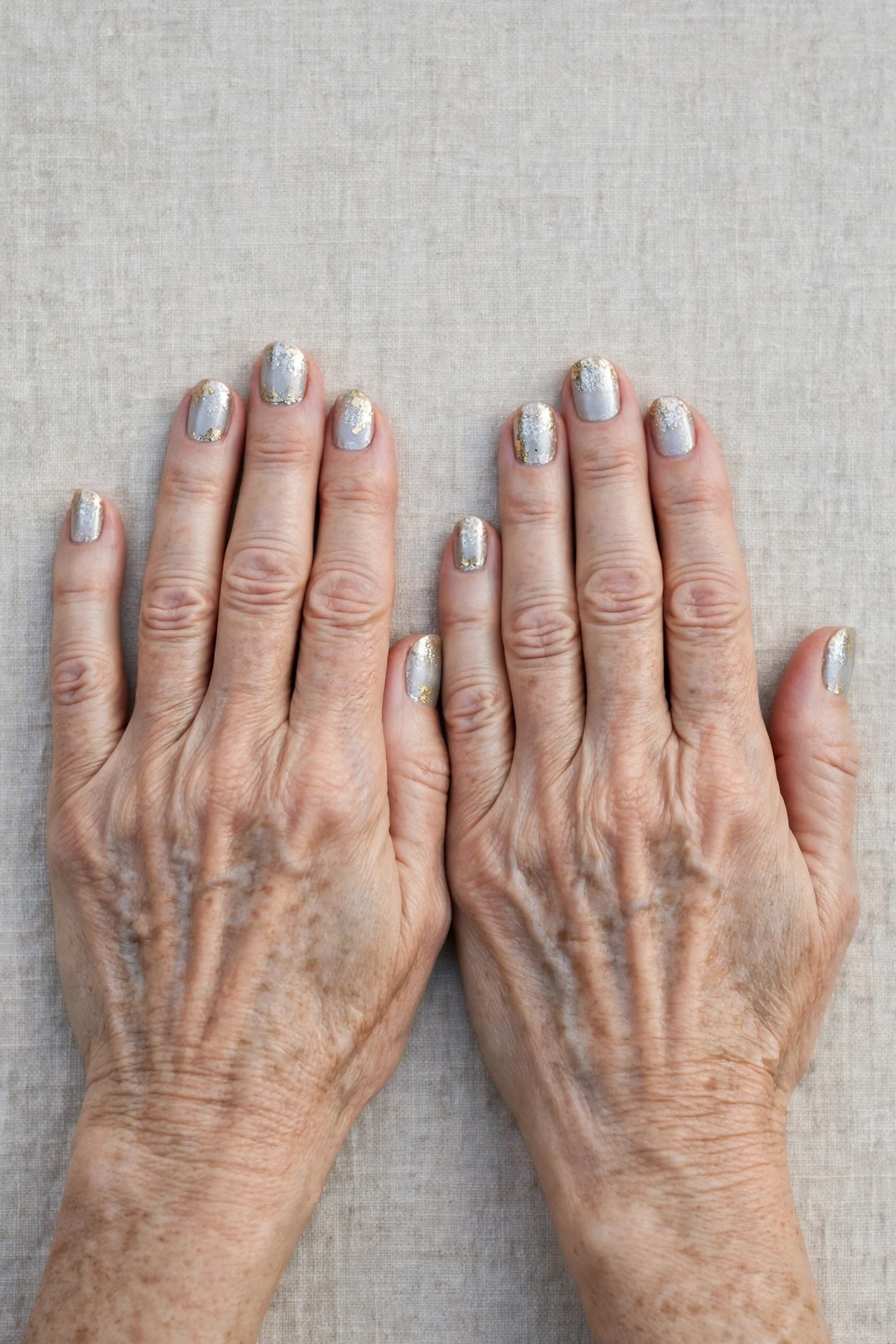 Short Oval Icy Silver Frosted Chrome Nails with a glitter gradient finish and gold foil accents