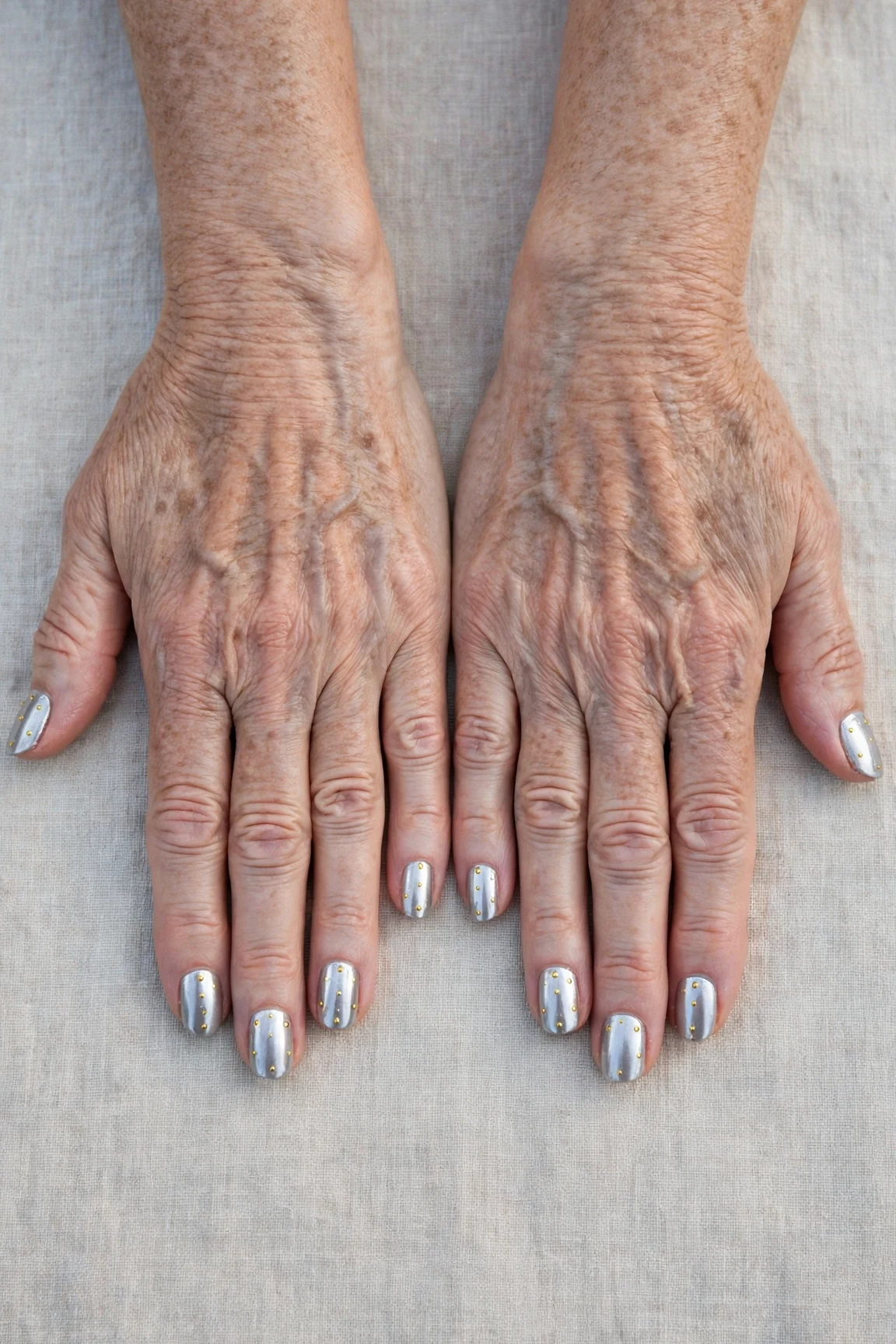 Short Oval Icy Silver Frosted Chrome Nails with a high-gloss finish and tiny gold dots