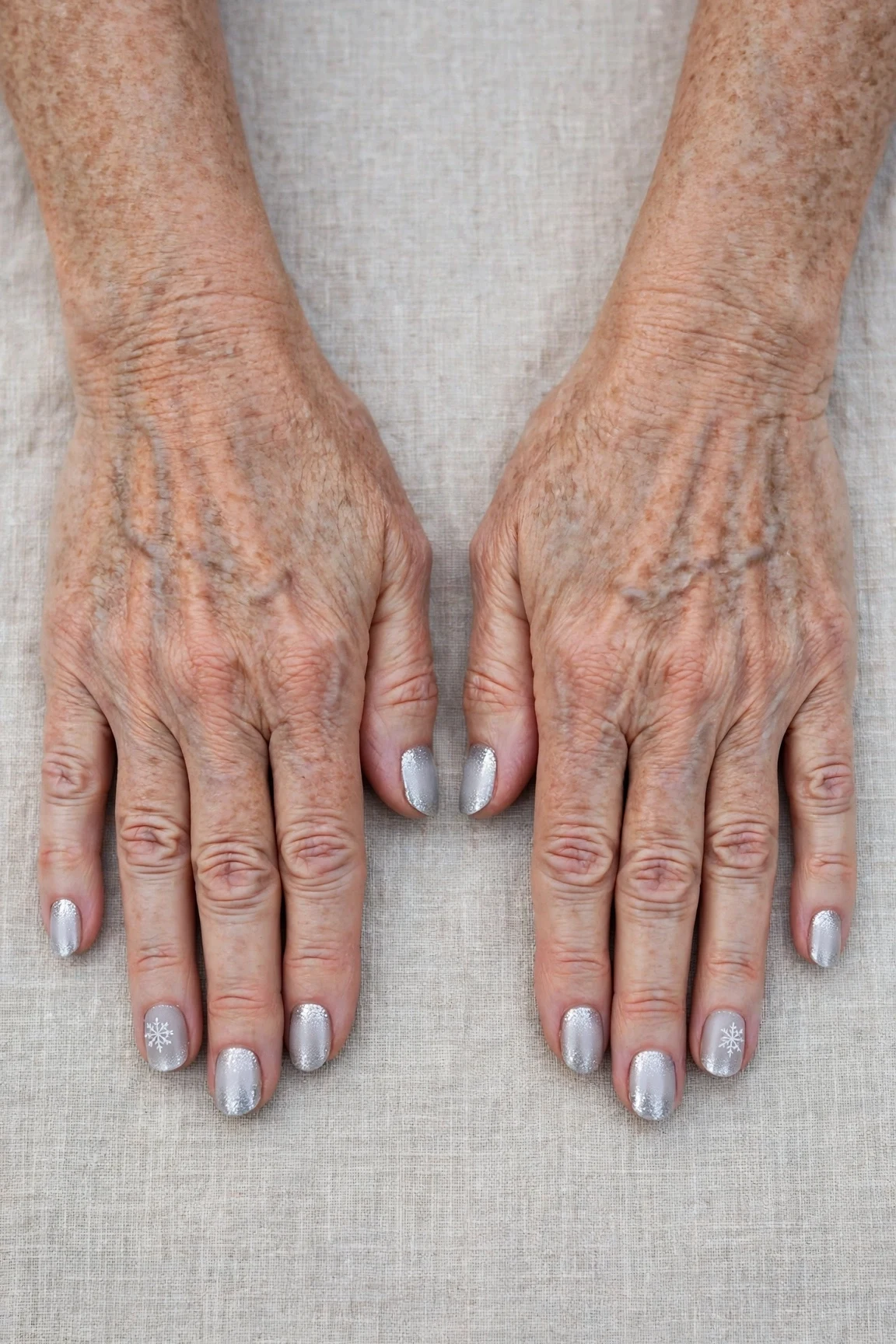 Short Oval Icy Silver Frosted Chrome Nails with a glitter gradient finish and a delicate snowflake on the ring finger