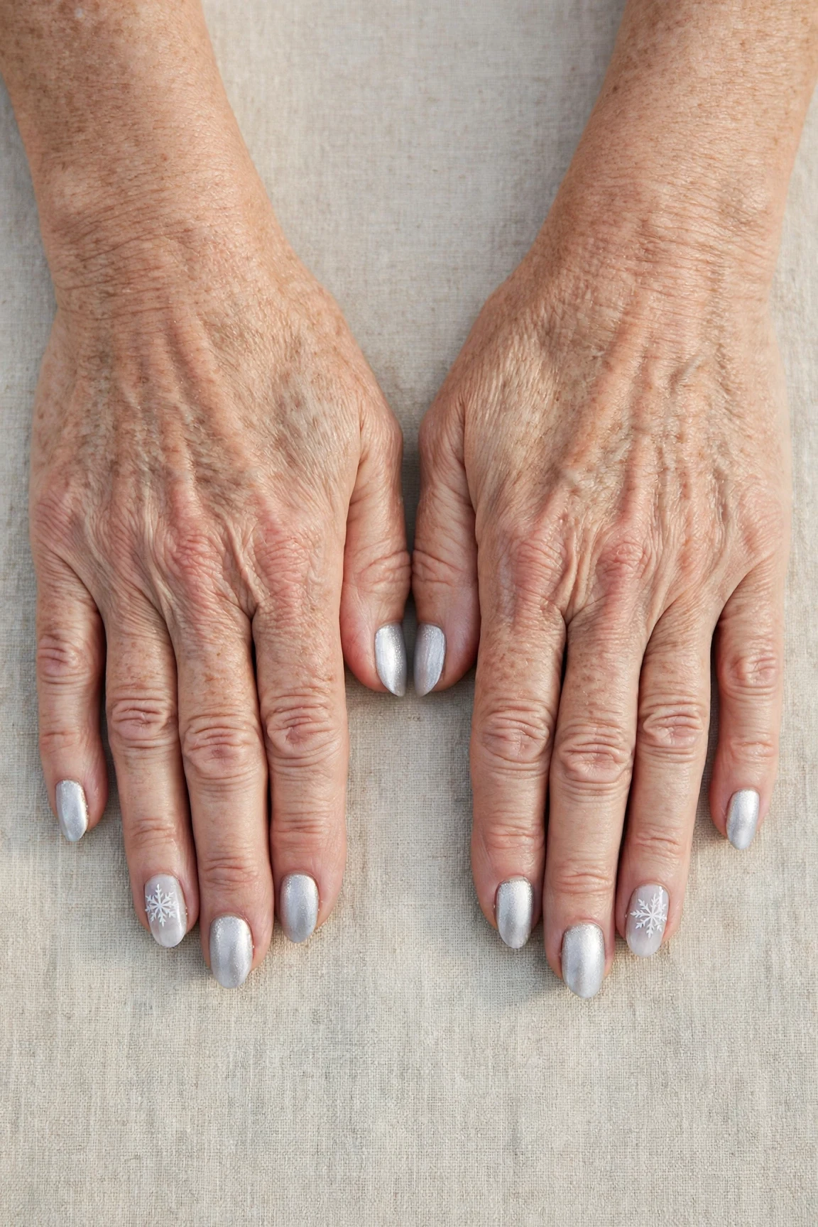 Almond Icy Silver Frosted Chrome Nails with a pearl shimmer finish and a delicate snowflake on the ring finger