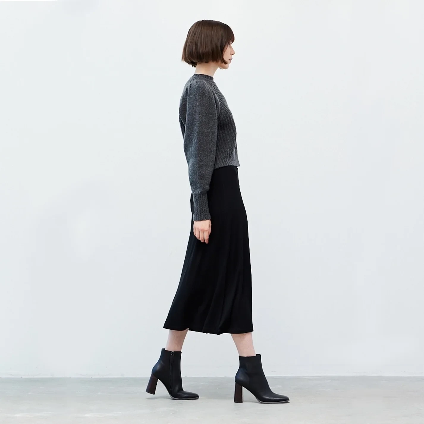 Grey Knit Sweater under a Charcoal Coat with Black Midi Skirt and Black Ankle Boots