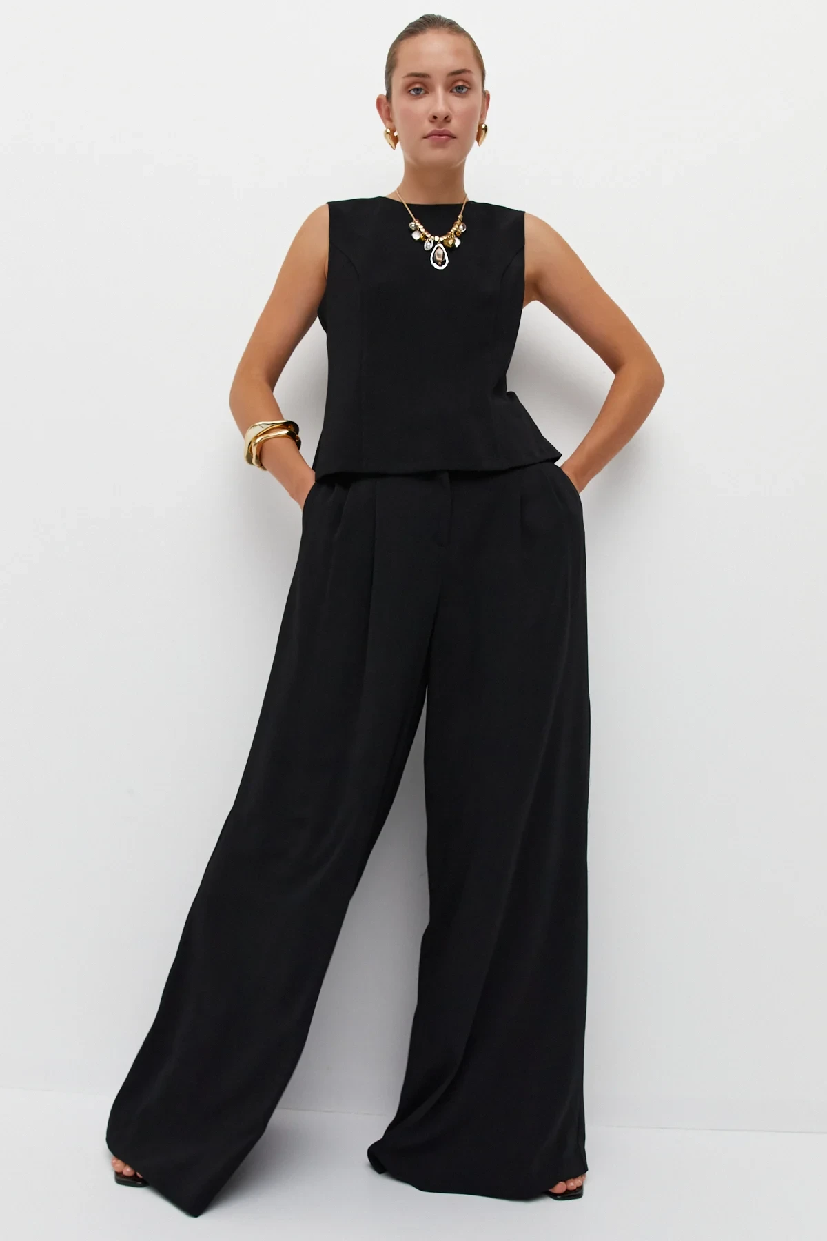 Black Peplum Knit Top and Wide-Leg Trousers with a gold pendant necklace