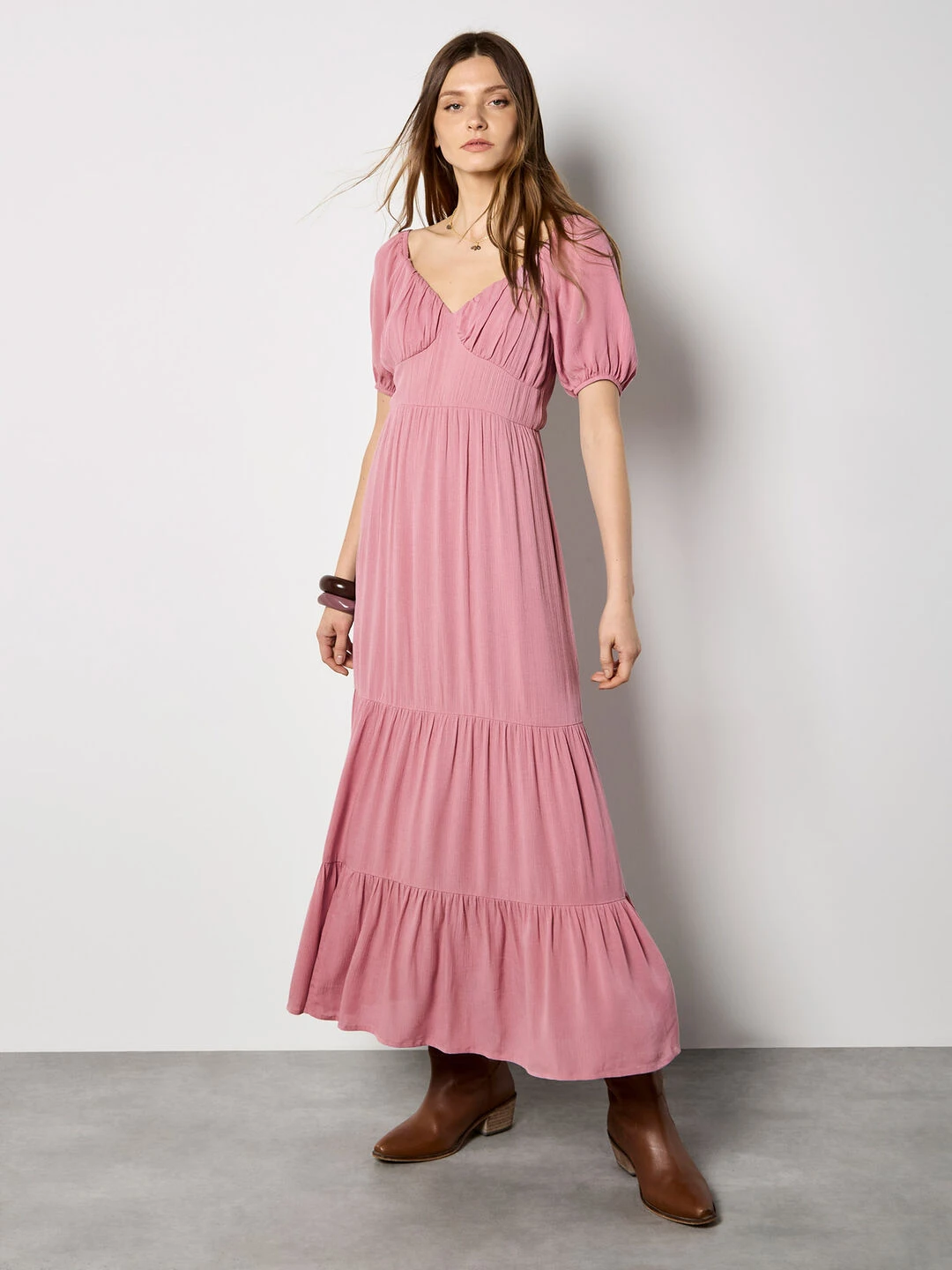 Pastel pink tiered skirt outfit with block-heel ankle boots and a delicate gold necklace