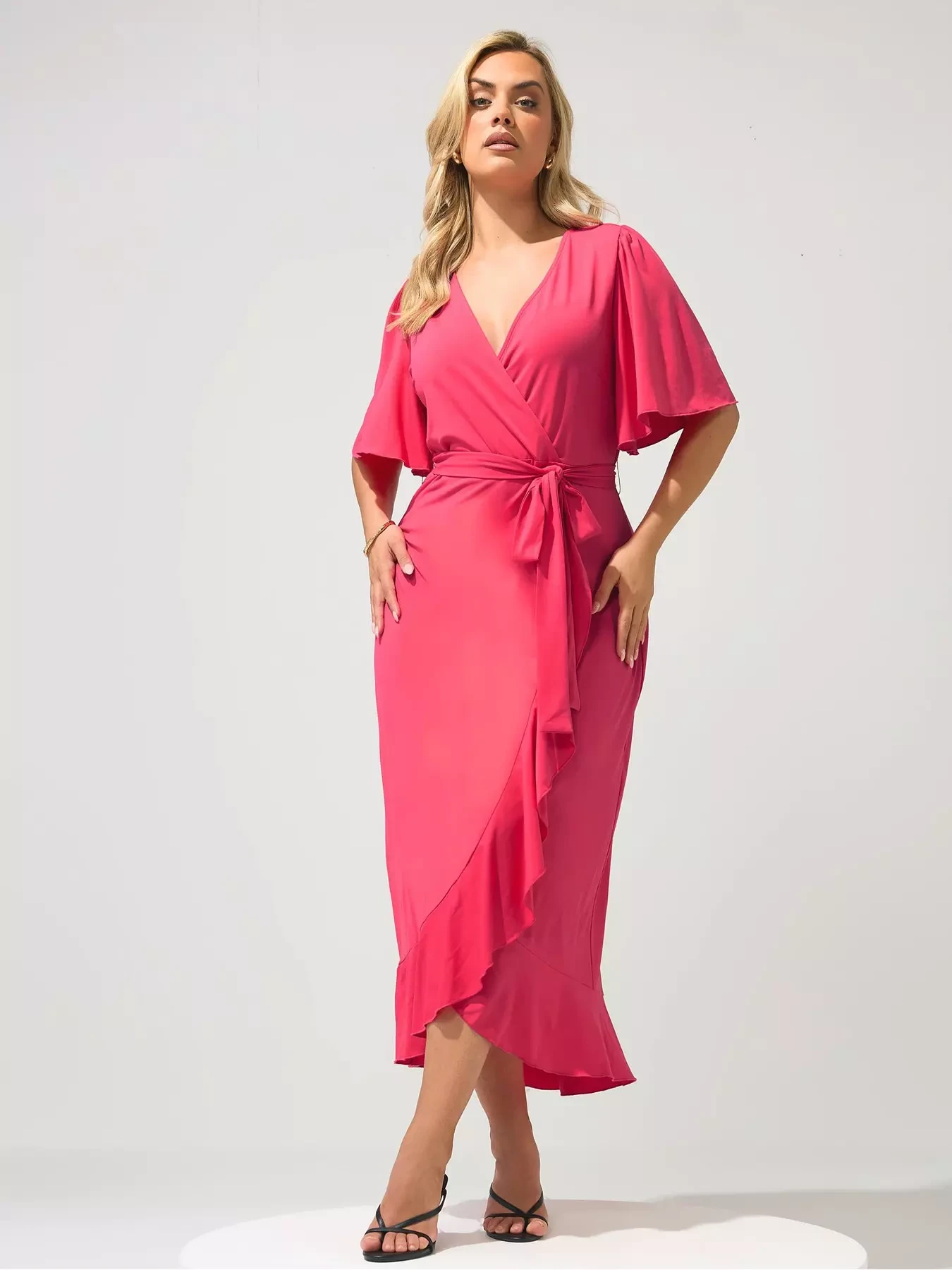38 Ruffle Hem Dress Outfits for Late Winter Weddings That Are Chic, Romantic and Easy to Wear 14 Pink ruffle hem wrap dress with black pointed heels and statement earrings