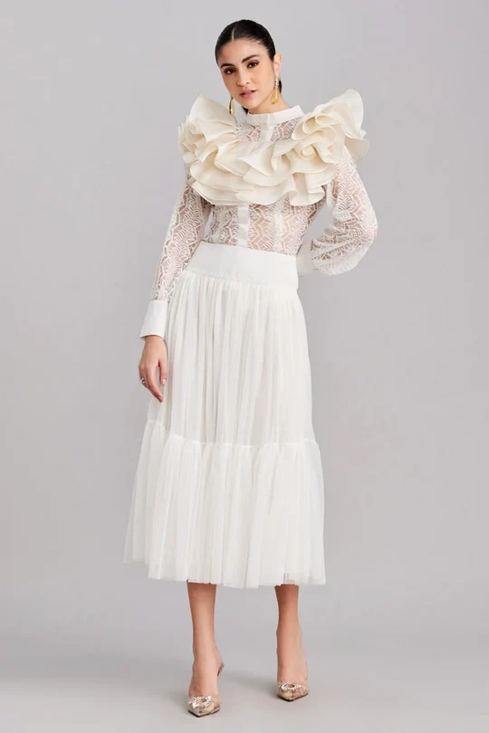 White ruffle knee-length skirt outfit with elegant pointed flats and statement earrings