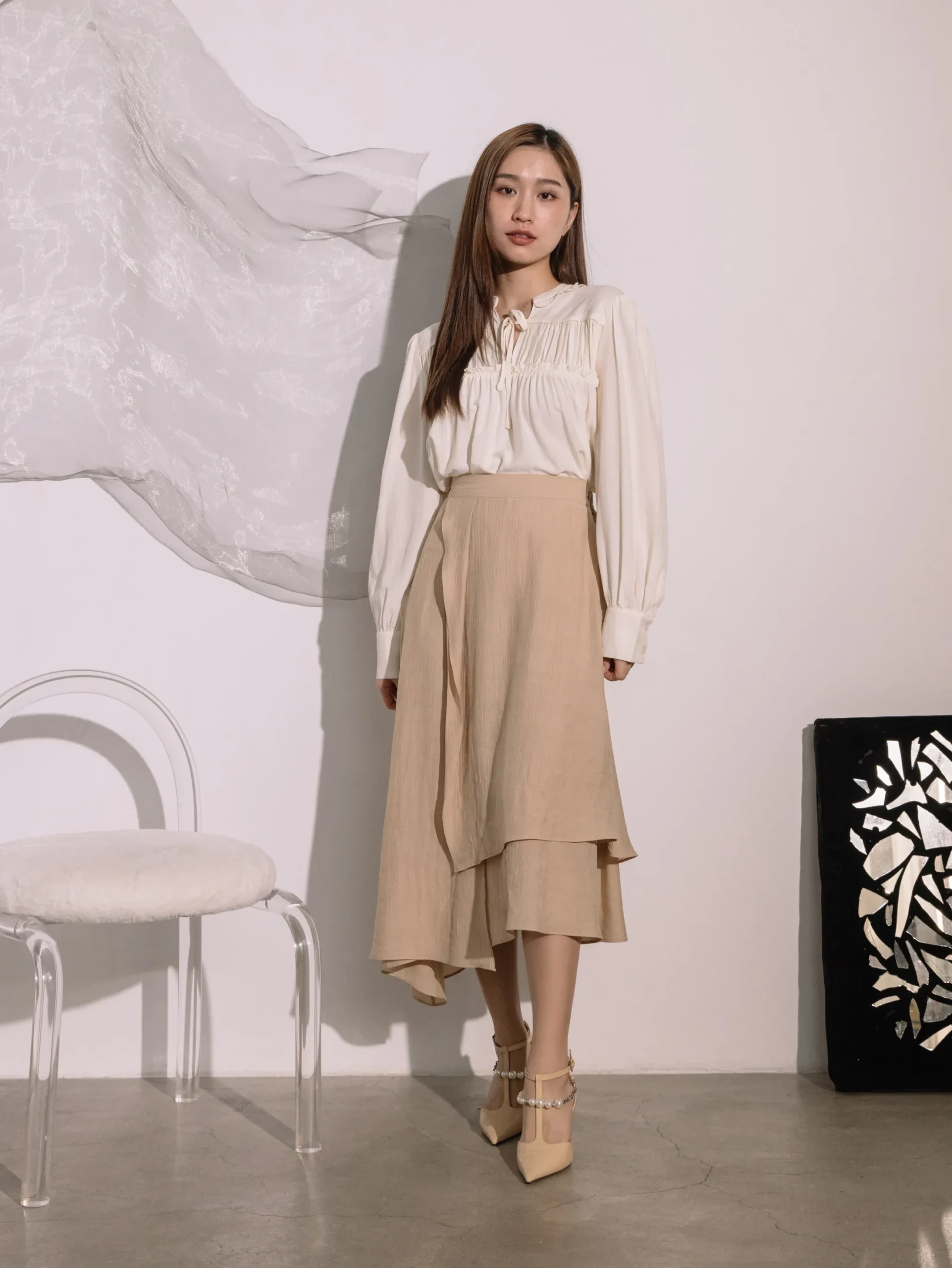 Cream ruffle sleeve top and wrap skirt outfit with elegant pointed flats and a pearl bracelet