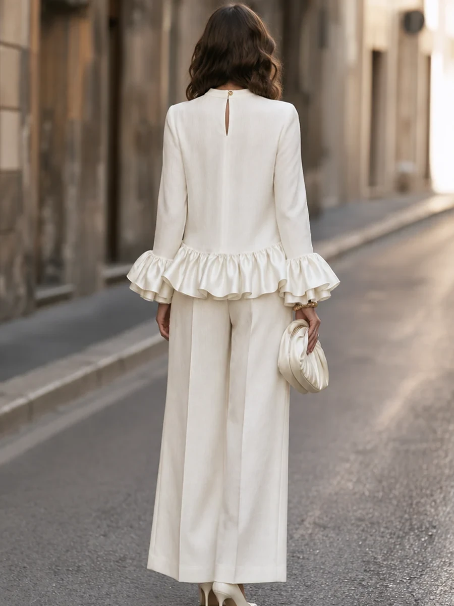 White ruffle sleeve top and satin trouser outfit with kitten heels and a pearl bracelet