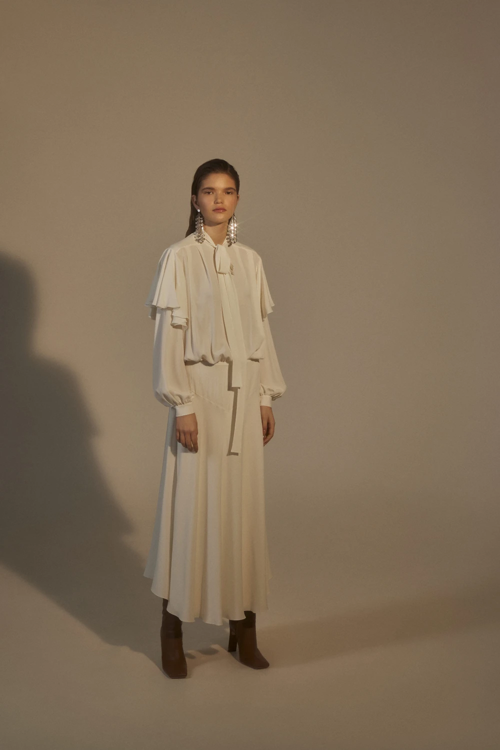 White ruffle sleeve top and wrap skirt outfit with block-heel ankle boots and statement earrings