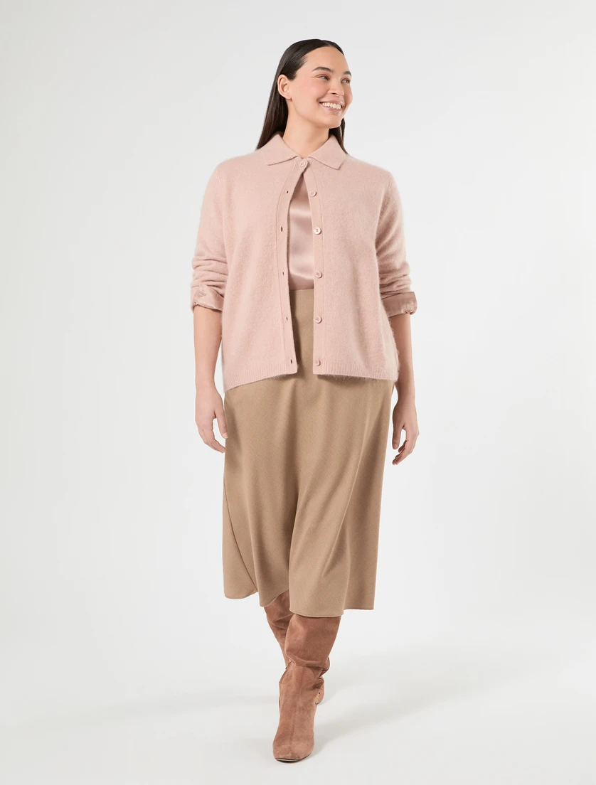 Soft pink knit cardigan outfit with a knee-length skirt, suede ankle boots and a small structured clutch