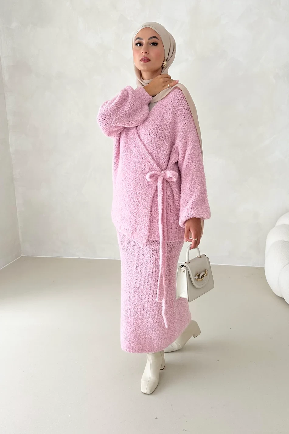 Pale soft pink knit and skirt outfit with block-heel ankle boots and a chic crossbody bag