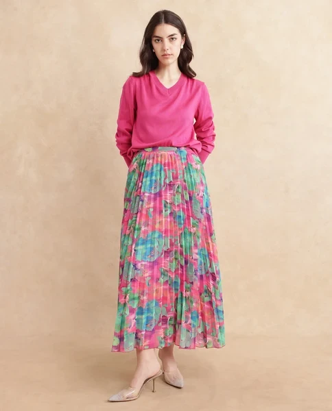 Blush pink sweater and pleated skirt outfit with black pointed heels and statement earrings