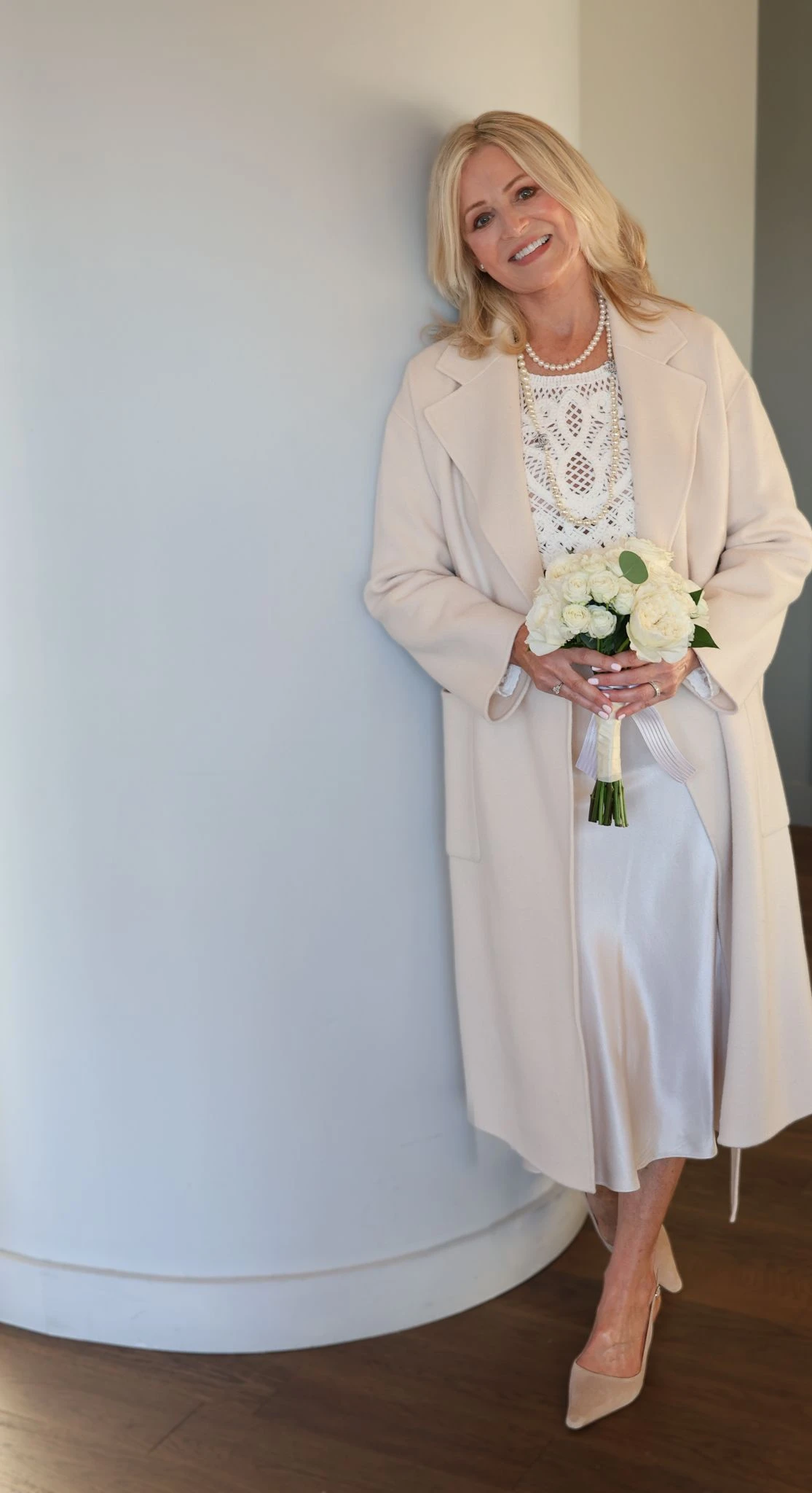 25 Wool Wrap Coat Outfits for Women Over 40 for Winter Weddings That Are Warm, Elegant and Effortlessly Chic 23 Cream Wool Coat with a White Satin Dress and Nude Heels for a Christmas Wedding